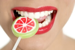 Colorful Lollypop in perfect woman teeth and red lips mouth